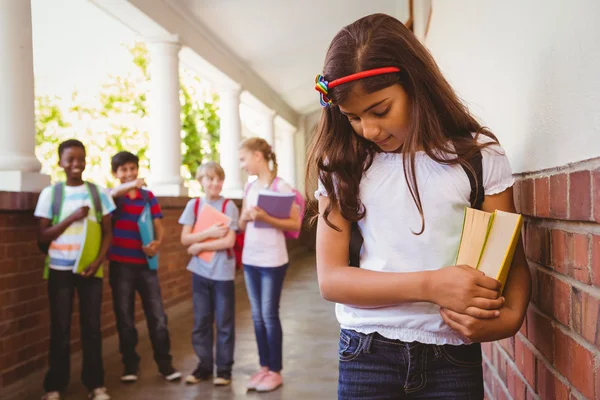 Triste écolière avec des amis en arrière-plan au couloir de l'école — Photo