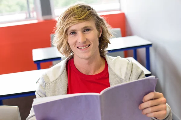 Male student reading notes in classroom — Stock Photo, Image