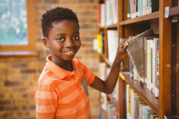 Portrait of boy selecting book in library — Stock Photo, Image