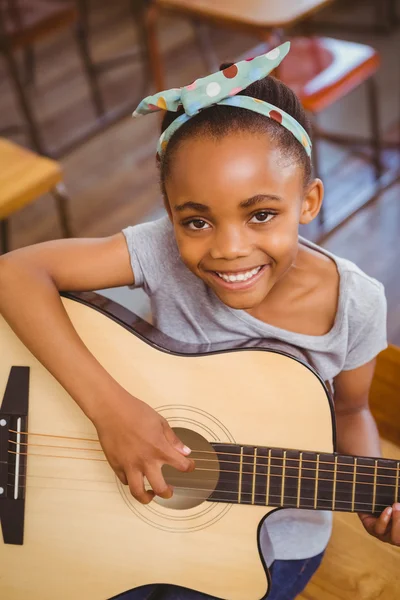 Liten flicka spela gitarr i klassrummet — Stockfoto