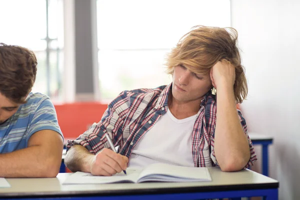 Männlicher Schüler schreibt Notizen im Klassenzimmer — Stockfoto