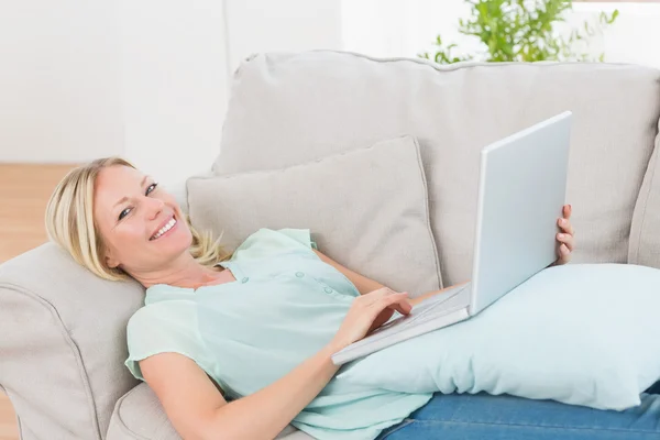 Vacker kvinna med laptop liggande på soffan — Stockfoto