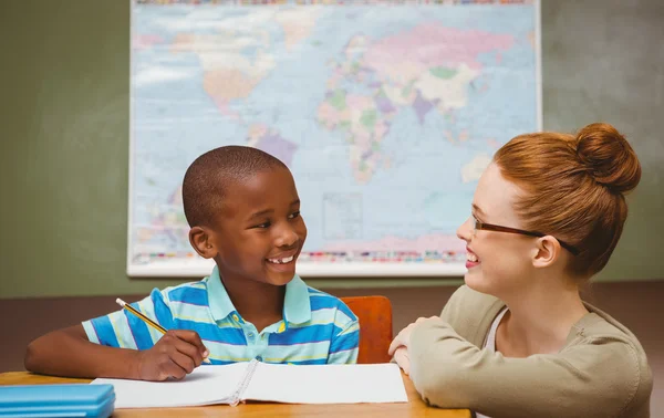 Profesor ayudando a niño pequeño con la tarea en el aula — Foto de Stock