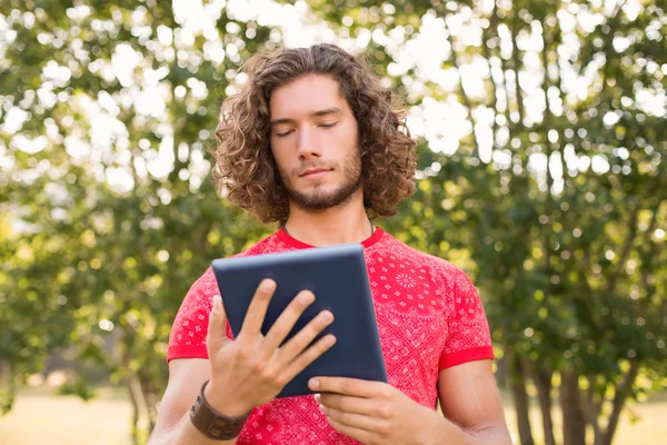 Bello hipster utilizzando tablet pc nel parco — Foto Stock