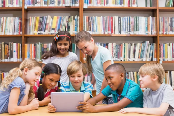 Симпатичные ученики с помощью планшетного компьютера в библиотеке — стоковое фото