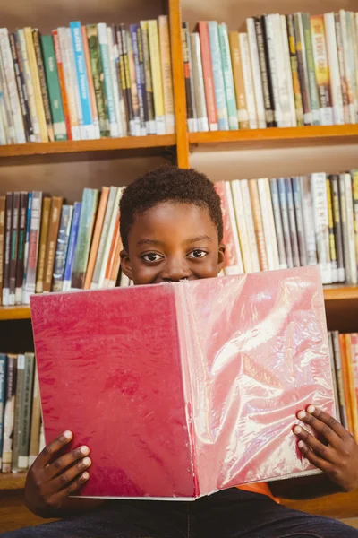 Bonito menino leitura livro na biblioteca — Fotografia de Stock