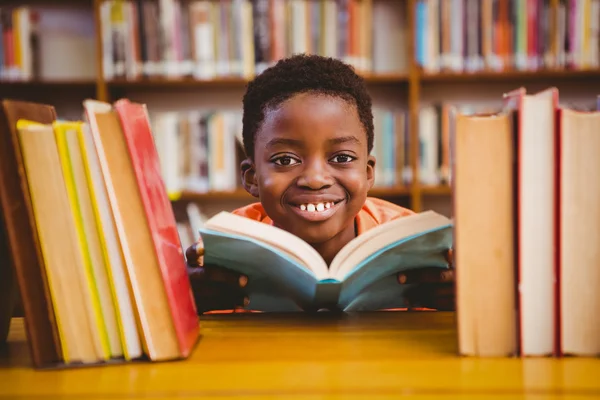 Cute boy reading book in library — Stock Photo, Image