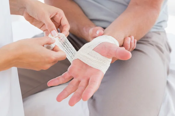 Doctor bandaging her patient hand — Stock Photo, Image