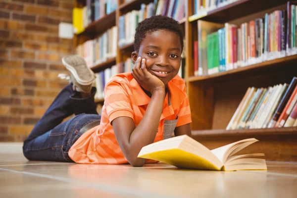 Симпатичный мальчик читает книги в библиотеке — стоковое фото