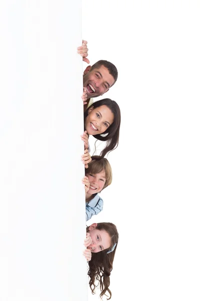 Glückliche Familie versteckt sich hinter Plakatwand — Stockfoto