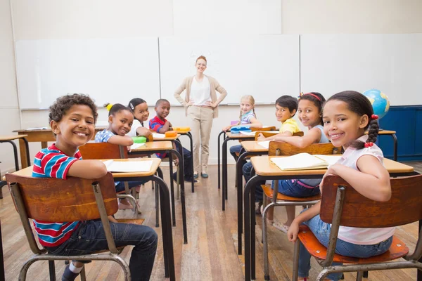 Söta elever ler mot kameran i klassrummet — Stockfoto