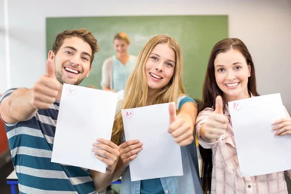 Щасливі студенти з паперами жестикулюють великими пальцями вгору — стокове фото