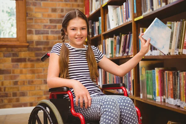 Fille en fauteuil roulant sélection livre dans la bibliothèque — Photo