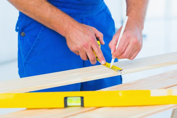 Carpenter marking on plank with tape measure — Stock Photo, Image