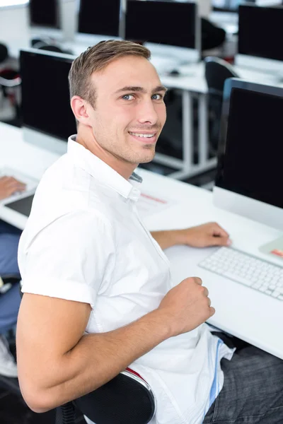 Φοιτητής να χαμογελά στη φωτογραφική μηχανή στην τάξη του υπολογιστή — Φωτογραφία Αρχείου