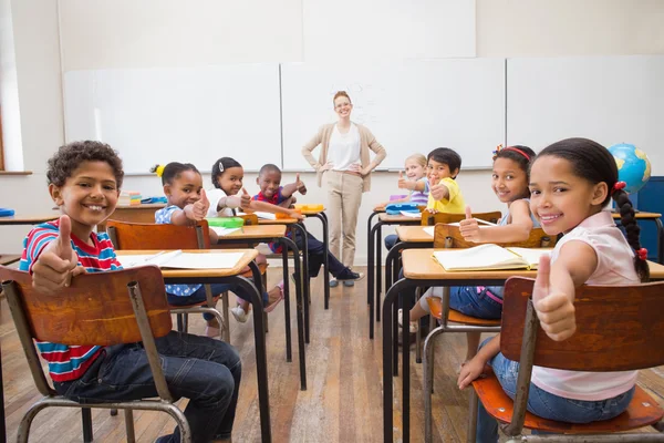 Söta elever ler mot kameran i klassrummet — Stockfoto