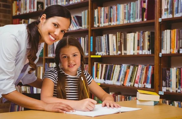 Nauczyciel wspomagający dziewczynki w odrabianiu prac domowych w bibliotece — Zdjęcie stockowe