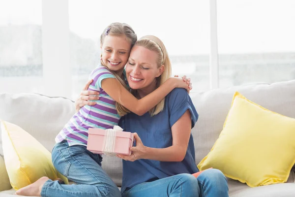 Mother with gift embracing daughter Stock Photo