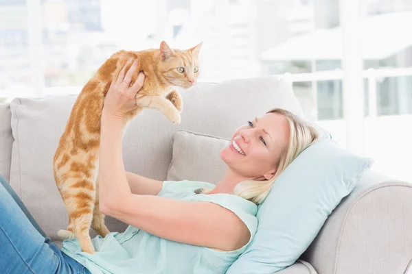 Woman lifting cat on sofa at home Stock Photo