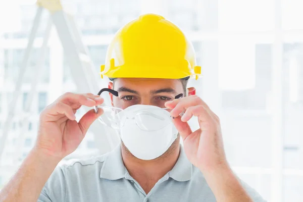 Handyman wearing protective eyewear at site Stock Picture