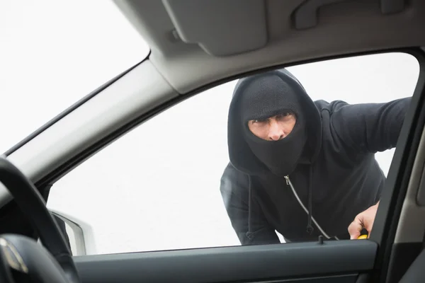 Thief breaking into car with screwdriver Royalty Free Stock Images