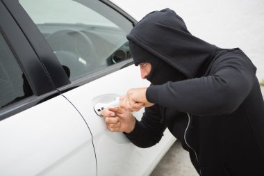 Thief breaking into car with screwdriver  clipart