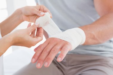 Doctor bandaging her patient hand clipart