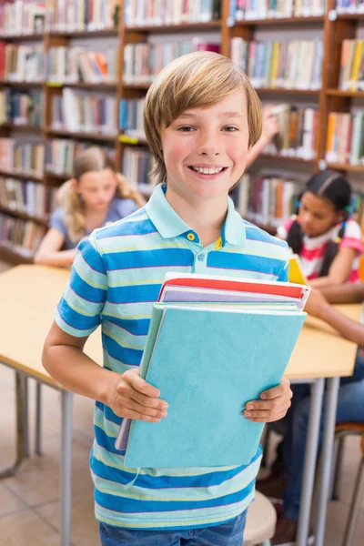 Aluno bonito sorrindo para a câmera na biblioteca — Fotografia de Stock