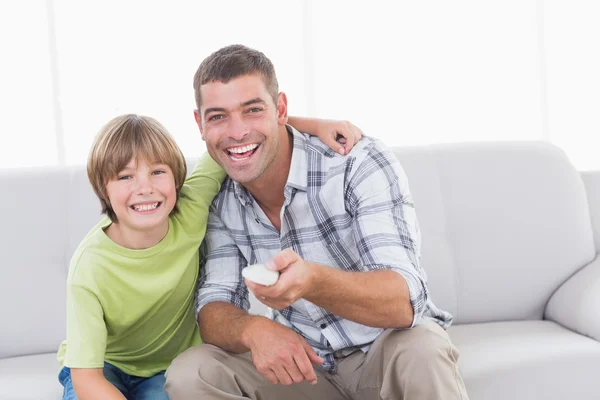 Happy father and son using remote control on sofa — Stock Photo, Image