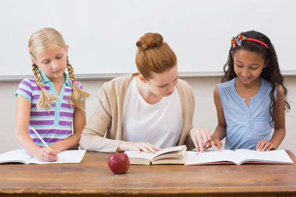 Teacher and pupils working at desk together — Stock Photo, Image