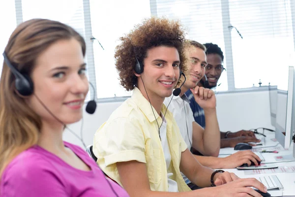 Estudiantes sonrientes usando auriculares en clase de informática — Foto de Stock