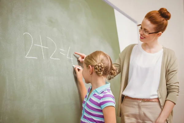 Insegnante che assiste la ragazza a scrivere sulla lavagna in classe — Foto Stock