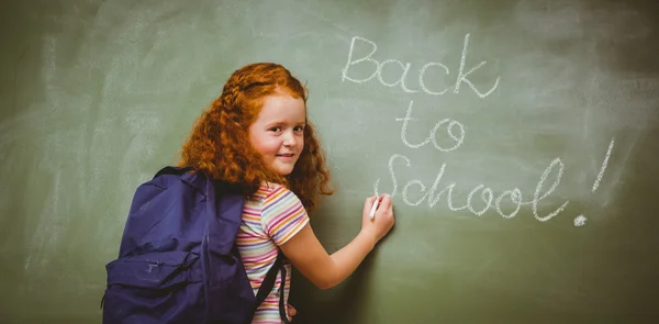 Portrait of cute little girl writing on blackboard — Stock Photo, Image