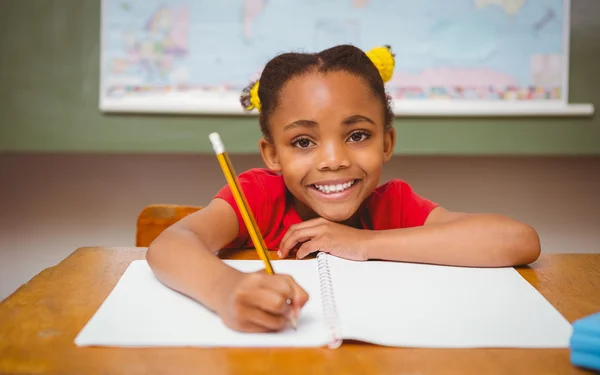 Kleine meisje schrijven boek in klas — Stockfoto