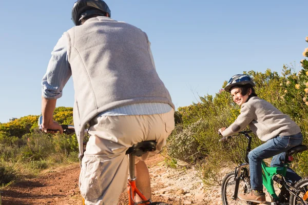 Vader en zoon op een fiets rijden o — Stockfoto
