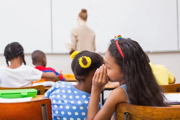 Cute pupils whispering in classroom — Stock Photo, Image