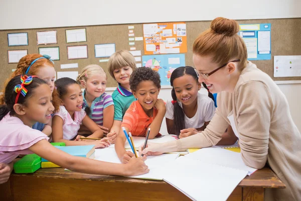 Teacher and pupils working at desk together — Stock Photo, Image