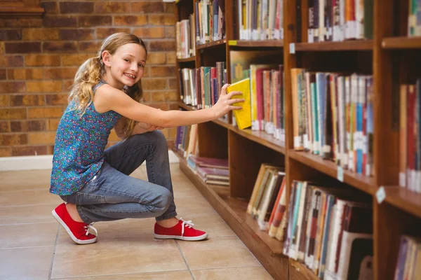 Милая маленькая девочка выбирает книгу в библиотеке — стоковое фото