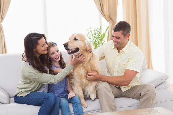 Famille caressant chien assis sur le canapé — Photo