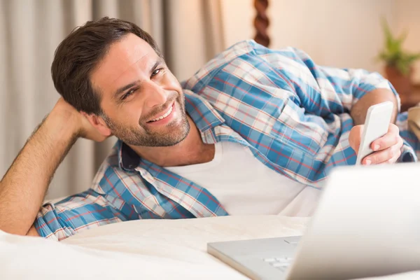 Homme se détendre sur le lit avec ordinateur portable — Photo