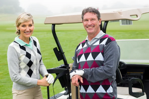 Golfing couple with golf buggy behind — Stock Photo, Image