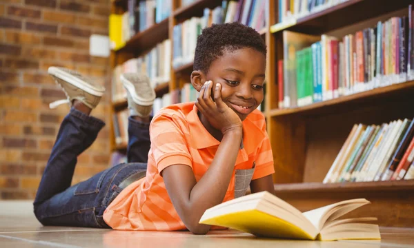 Bonito menino leitura livro na biblioteca — Fotografia de Stock