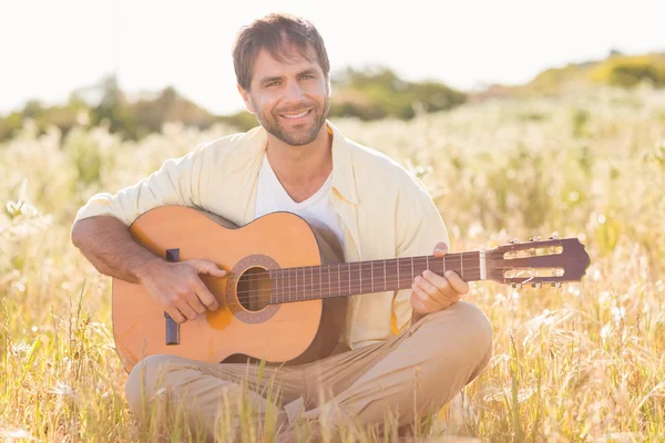 Lycklig man ler och spelar gitarr — Stockfoto