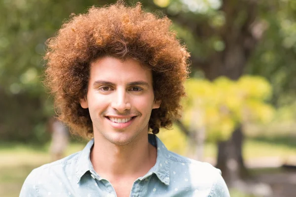 Giovane uomo sorridente alla macchina fotografica nel parco — Foto Stock