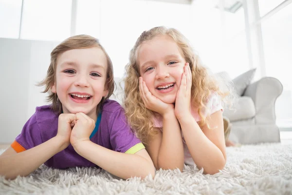 Happy siblings lying on rug at home — Stock Photo, Image