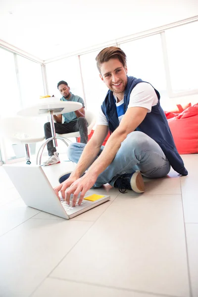 Sorrindo jovem usando laptop no chão — Fotografia de Stock