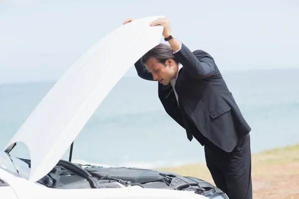 Stressed businessman looking at engine — Stock Photo, Image