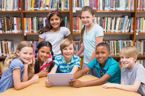 Roztomilý žáků pomocí tabletového počítače v knihovně — Stock fotografie