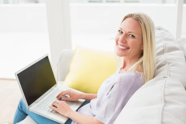 Lachende vrouw op de Bank met behulp van laptop — Stockfoto