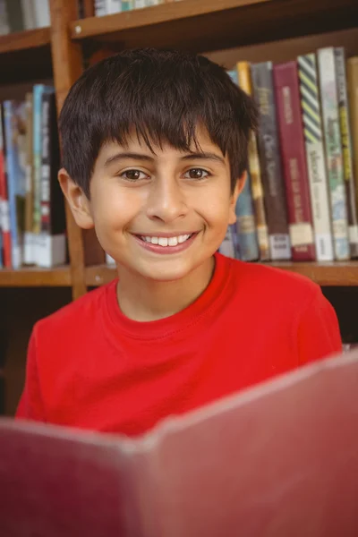 Carino ragazzo lettura libro in biblioteca — Foto Stock